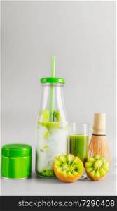 Healthy vegan layered matcha latte drink in bottle with drinking straw standing on table at light gray background. Matcha espresso. Clean eating, detox beverage, dairy food concept. Summer drinks