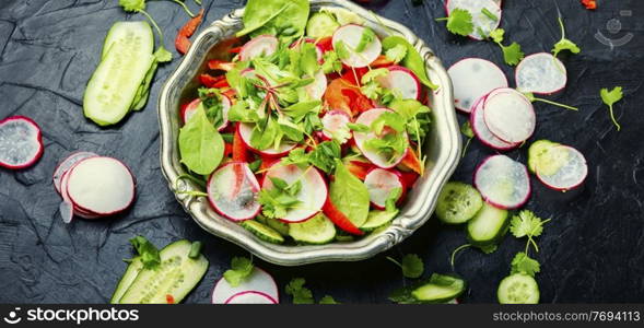 Healthy vegetable salad made from radish,pepper,cabbage and greens. Summer vitamin salad on a metal plate