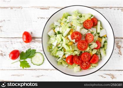 Healthy vegetable salad of chinese cabbage, corn, cucumbers and tomatoes. Delicious vegetarian dietary lunch. Vegan food. Top view. Flat lay