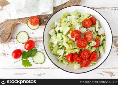 Healthy vegetable salad of chinese cabbage, corn, cucumbers and tomatoes. Delicious vegetarian dietary lunch. Vegan food. Top view. Flat lay