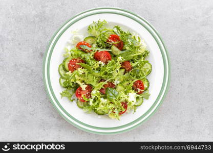 Healthy vegetable salad of fresh tomato, cucumber, spinach, frize and sesame on plate. Diet menu. Top view.