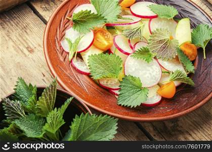 Healthy vegetable salad of nettle on plate.. Vitamin salad on a wooden background