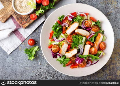Healthy vegetable salad with grilled chicken breast, fresh lettuce, cherry tomatoes, red onion and pepper