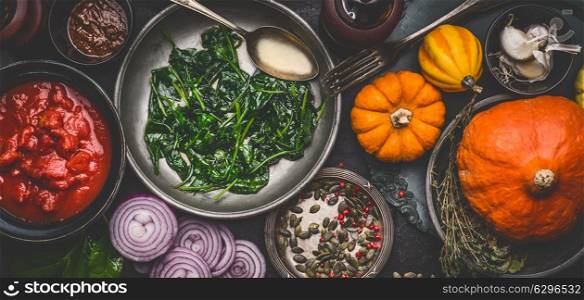 Healthy vegetarian cooking ingredients for tasty pumpkin dishes recipes in bowls : tomato sauces, spinach, sliced onion, pumpkin seeds, top view, banner. Clean seasonal eating