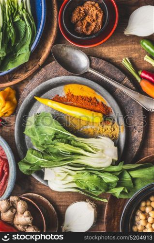 Healthy vegetarian cooking ingredients with colorful ground spices , chick peas, spicy indian curry paste , greens, ginger, vegetables and spoon. Healthy food and eating or Indian cuisine concept