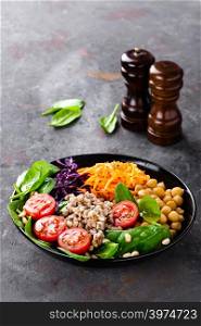 Healthy vegetarian dish with buckwheat and vegetable salad of chickpea, kale, carrot, fresh tomatoes, spinach leaves and pine nuts. Buddha bowl. Balanced food. Delicious detox diet