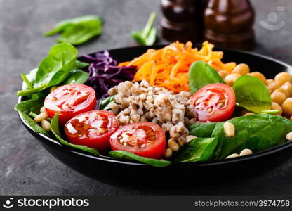 Healthy vegetarian dish with buckwheat and vegetable salad of chickpea, kale, carrot, fresh tomatoes, spinach leaves and pine nuts. Buddha bowl. Balanced food. Delicious detox diet