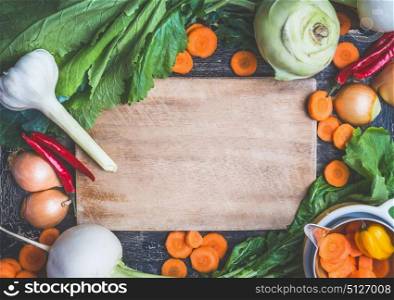 Healthy vegetarian eating and cooking with fresh organic ingredients. Various farm vegetables, Herbs,spices around rustic wooden gutting board background, top view, frame