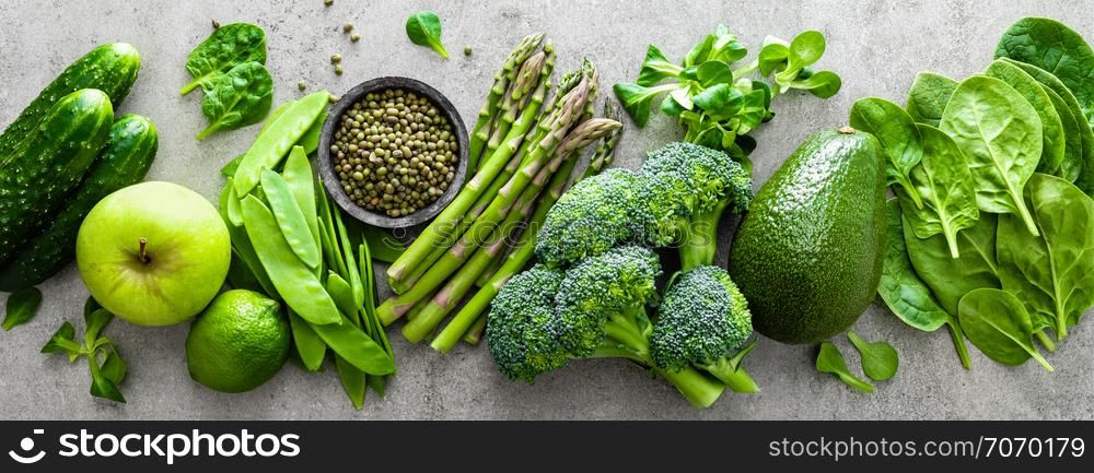 Healthy vegetarian food concept background, fresh green food selection for detox diet, raw broccoli, apple, cucumber, spinach, peas, asparagus, avocado, lime, corn salad and mung bean, view from above, flat lay, banner