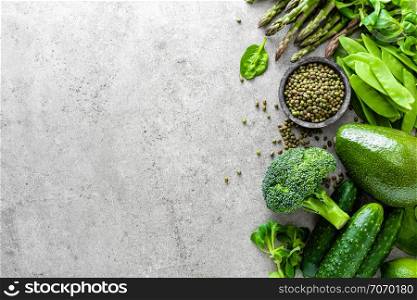 Healthy vegetarian food concept background, fresh green food selection for detox diet, raw broccoli, apple, cucumber, spinach, peas, asparagus, avocado, lime, corn salad and mung bean, view from above, flat lay