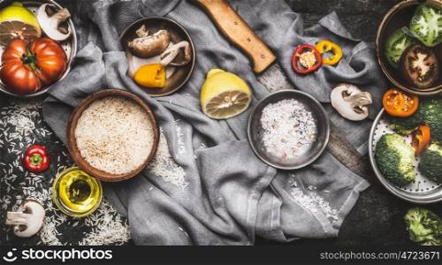 Healthy vegetarian food ingredients with lemon, rice and vegetables on dark rustic background, top view