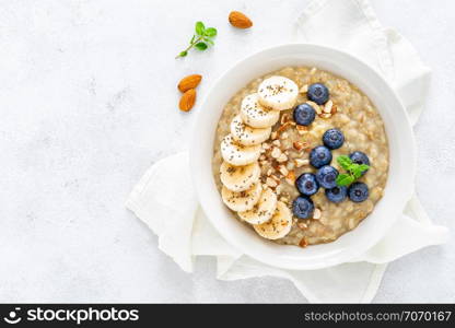 Healthy vegetarian food, oatmeal with fresh blueberry, banana, almond nuts and chia seeds for breakfast, view from above