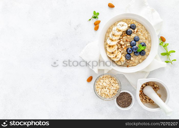 Healthy vegetarian food, oatmeal with fresh blueberry, banana, almond nuts and chia seeds for breakfast, view from above