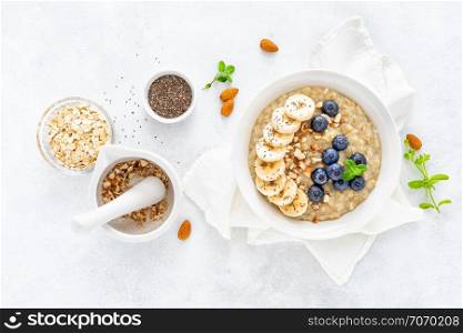 Healthy vegetarian food, oatmeal with fresh blueberry, banana, almond nuts and chia seeds for breakfast, view from above