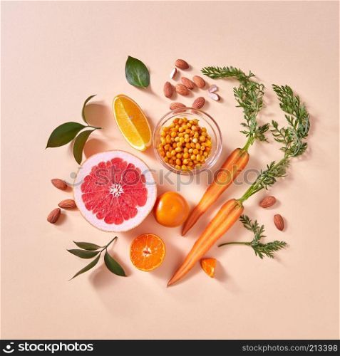 Healthy vegetarian food - orange organic vegetables and fruits on a paper background. Top view. Concept of organic natural vegetarian food.. Natural organic citrus fruits, carrots, sea buckthorn berries - ingredients for making homemade detox smoothie on yellow paper background.