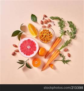 Healthy vegetarian food - orange organic vegetables and fruits on a paper background. Top view. Concept of organic natural vegetarian food.. Natural organic citrus fruits, carrots, sea buckthorn berries - ingredients for making homemade detox smoothie on yellow paper background.