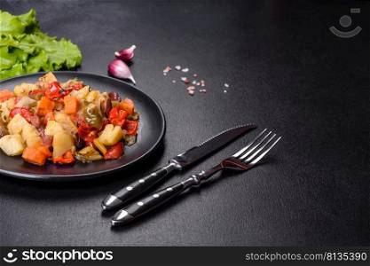 Healthy vegetarian lunch - stewed garden vegetables. Vegetable ratatouille. Vegetable stew or ratatouille with eggplant, tomatoes, sweet and hot peppers, onions, carrots and spices in plate