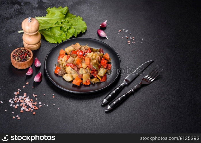 Healthy vegetarian lunch - stewed garden vegetables. Vegetable ratatouille. Vegetable stew or ratatouille with eggplant, tomatoes, sweet and hot peppers, onions, carrots and spices in plate