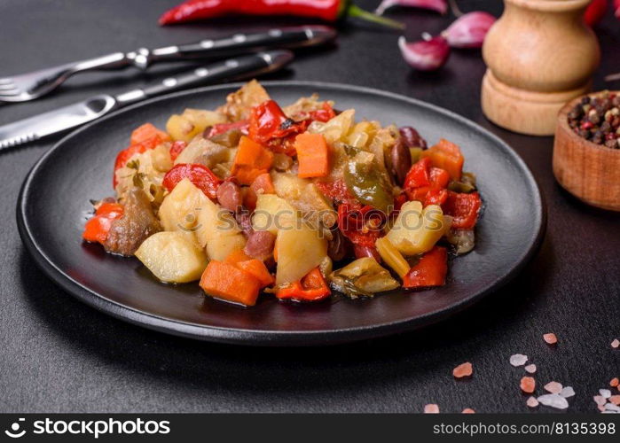 Healthy vegetarian lunch - stewed garden vegetables. Vegetable ratatouille. Vegetable stew or ratatouille with eggplant, tomatoes, sweet and hot peppers, onions, carrots and spices in plate