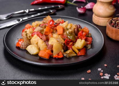 Healthy vegetarian lunch - stewed garden vegetables. Vegetable ratatouille. Vegetable stew or ratatouille with eggplant, tomatoes, sweet and hot peppers, onions, carrots and spices in plate