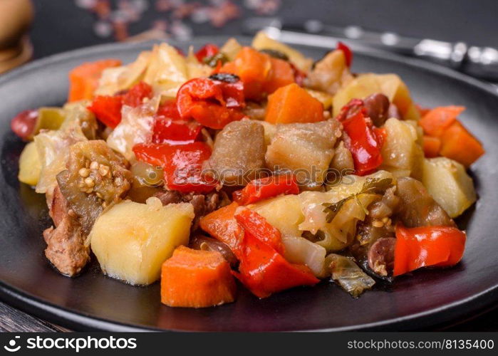 Healthy vegetarian lunch - stewed garden vegetables. Vegetable ratatouille. Vegetable stew or ratatouille with eggplant, tomatoes, sweet and hot peppers, onions, carrots and spices in plate