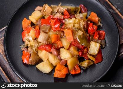 Healthy vegetarian lunch - stewed garden vegetables. Vegetable ratatouille. Vegetable stew or ratatouille with eggplant, tomatoes, sweet and hot peppers, onions, carrots and spices in plate