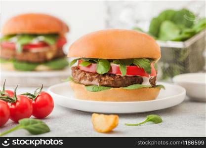 Healthy vegetarian meat free burgers on round ceramic plate with vegetables and spinach on light background..