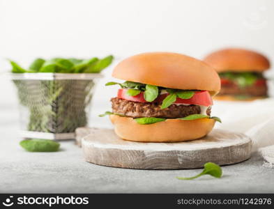 Healthy vegetarian meat free burgers on round chopping board with vegetables and spinach on light background.