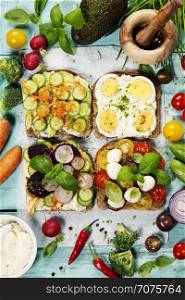 Healthy Vegetarian Sandwiches (with Avocado, Tomato, Cucumber, Onion, Beetroot, Cream Cheese, Herbs and Spices) on blue rustic background