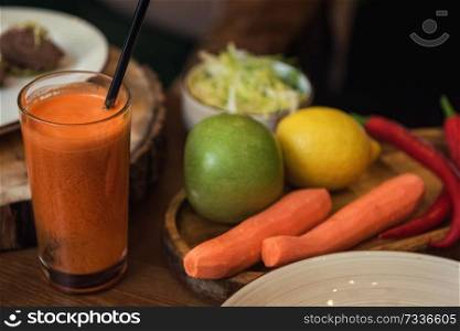 Healthy vegeterian food on brown wood board. Spring vitamin dieting food. Fruit and raw vagetables and carrot juice. Healthy vegeterian food