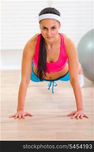 Healthy woman making push-up exercises at living room&#xA;
