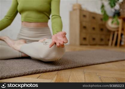 Healthy woman practicing meditation and relaxation yoga exercise indoors. Sportswoman doing Ardha Padmasana with mudra gesture for chakra harmony achievement. Crop shot. Healthy woman practicing meditation and relaxation yoga exercise indoors