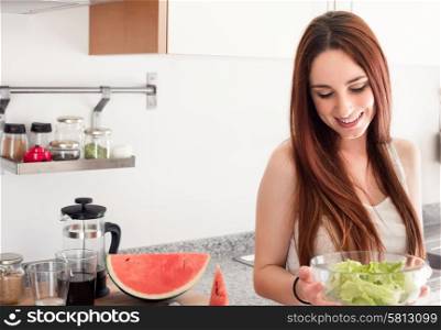 Healthy woman preparing a fresh salad in kitchen