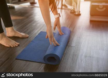 Healthy woman rolling preparing yoga mat for fitness class
