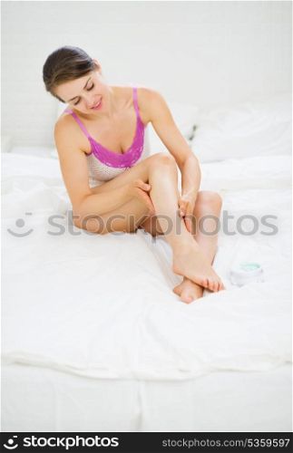 Healthy woman sitting in bed and checking her leg