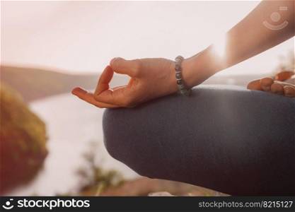 Healthy woman sitting in lotus pose and meditating on high cliff above river. Calm yoga concept, zen, relaxation, practice on nature background. High quality photo. Healthy woman sitting in lotus pose and meditating on high cliff above river. Calm yoga concept, zen, relaxation, practice on nature background.