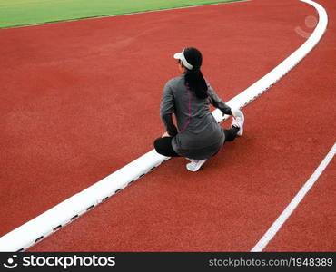 Healthy woman warming up, stretching her leg muscles in the public stadium before jogging. Workout Healthy lifestyle concept.