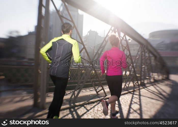 healthy young couple jogging in the city at early morning with sunrise in background