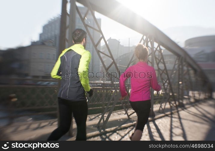 healthy young couple jogging in the city at early morning with sunrise in background