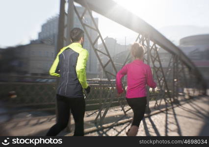 healthy young couple jogging in the city at early morning with sunrise in background