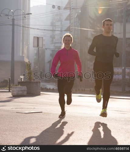 healthy young couple jogging in the city at early morning with sunrise in background