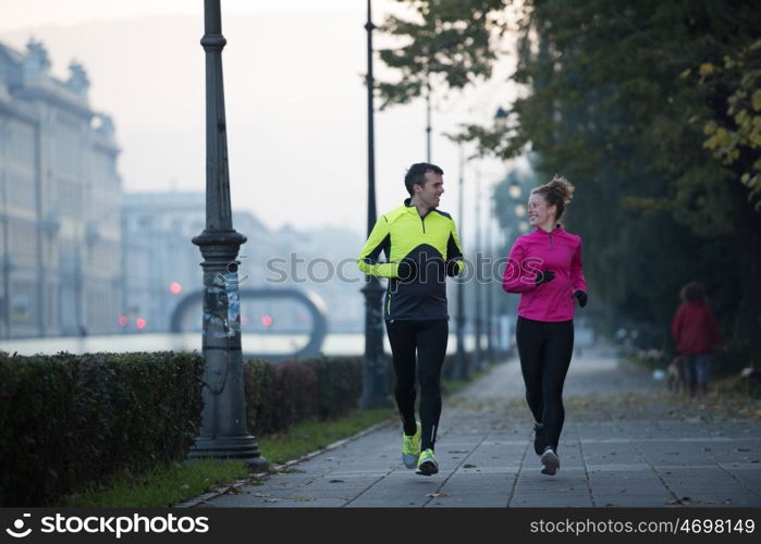 healthy young couple jogging in the city at early morning with sunrise in background