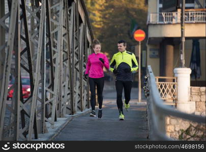 healthy young couple jogging in the city at early morning with sunrise in background