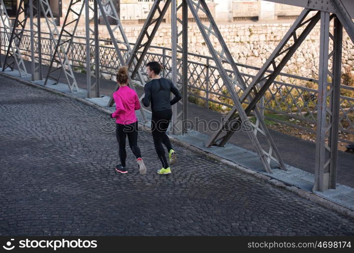 healthy young couple jogging in the city at early morning with sunrise in background