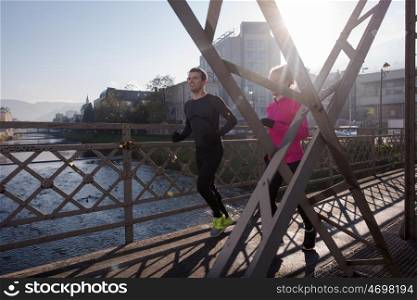 healthy young couple jogging in the city at early morning with sunrise in background