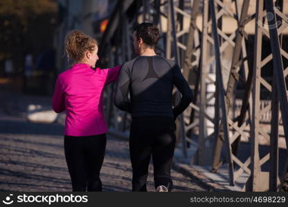 healthy young couple jogging in the city at early morning with sunrise in background