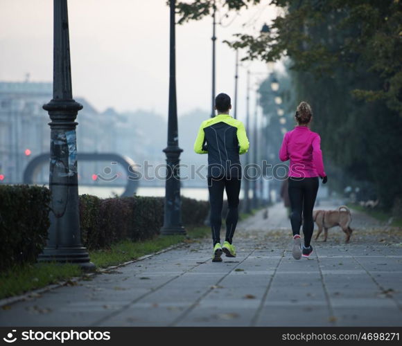 healthy young couple jogging in the city at early morning with sunrise in background