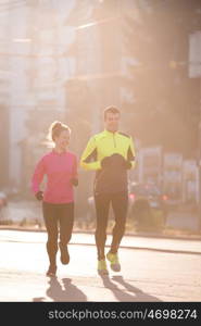 healthy young couple jogging in the city at early morning with sunrise in background