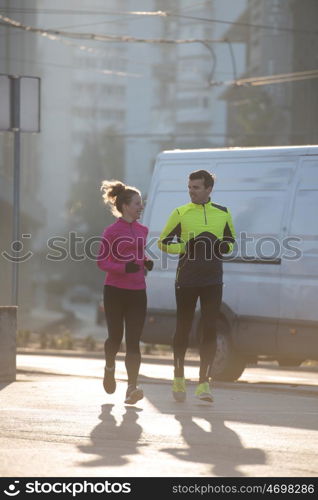 healthy young couple jogging in the city at early morning with sunrise in background