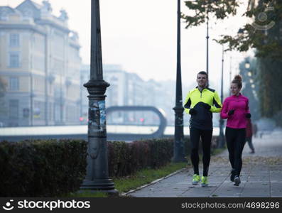 healthy young couple jogging in the city at early morning with sunrise in background